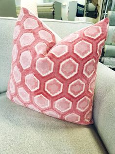 a pink and white pillow sitting on top of a couch