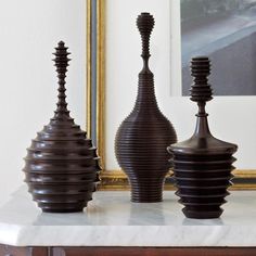 three brown vases sitting on top of a white table next to a framed photo