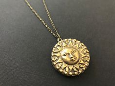 Bold Sun Hidden Locket Necklace... This celestial sun locket has an antique brass finish and is attached to an antique brass round locket. The chain is a non tarnish soldered antique brass rolo chain that closes with a lobster claw clasp. This is a unisex locket and would be a great gift for women and men! Locket - 1.25 inches in diameter (31.75mm) Interior photo area - 24mm Chain - 24 inches long This beautiful celestial locket will be mailed to you gift wrapped. A great gift to give your bride Vintage Brass Jewelry With Sun And Moon Design, Vintage Sun Design Jewelry Gift, Adjustable Vintage Jewelry With Sun Design, Bohemian Gold Brass Locket Necklace, Bronze Bohemian Locket Necklace, Bohemian Brass Locket Necklace With Vintage Charm, Antique Gold Medallion Locket Necklace In Bohemian Style, Antique Gold Bohemian Medallion Locket Necklace, Bohemian Brass Medallion Locket Necklace