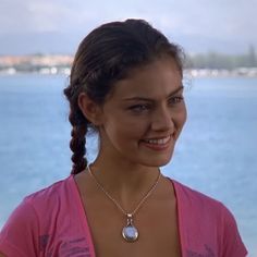 a woman standing by the water with a necklace on her neck