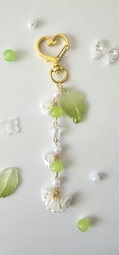 a gold key chain with green and white beads hanging from it's side on a table