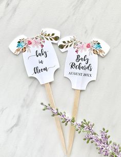 two baby in bloom hand fan on top of a table next to some purple flowers