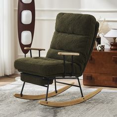 a green rocking chair sitting on top of a rug next to a wooden floor lamp