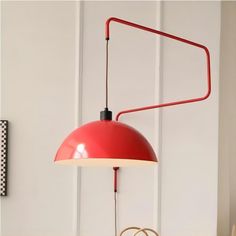 a red lamp hanging from the side of a white wall