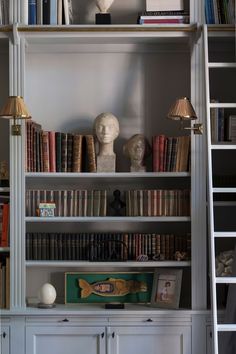 a bookshelf filled with lots of books next to a lamp and other items