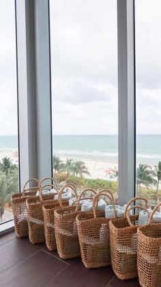 wicker baskets lined up on the floor in front of large windows with ocean view