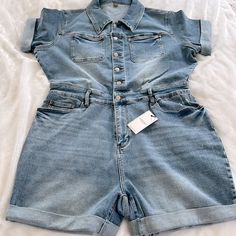 This Judy Blue Jumper Is A Light-Medium Wash Denim With Buttons Down The Top, A Stretchy Band Across The Waist And A Zipper Fly. The Arm And Short Hems Are Cuffed, And There Are Pockets On The Chest And Front And Back Of The Shorts. The 2x Measures About 24” From Underarm To Underarm, About 19” Across The Waist, And Has An Inseam Of About 5”. The 3x Measures About 25” From Underarm To Underarm, About 20” Across The Waistband, And Has An Inseam Of About 5.5”. B2 Fitted Light Wash Jean Shorts With Pockets, Fitted High Waist Shortalls For Spring, High Rise Denim Shortalls For Spring, Fitted Medium Wash Shortalls For Spring, High Waist Denim Shortalls For Spring, Spring Shortalls In Dark Wash, Fitted Denim Blue Shortalls With Pockets, Fitted Denim Shortalls In Light Wash, Denim Overalls With Pockets In Short Length