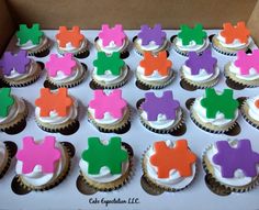 cupcakes with colorful frosting shaped like elephants on top are displayed in a box