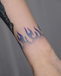 a tattoo on the arm of a person with blue flames coming out of their arms