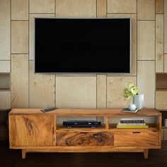 an entertainment center with a flat screen tv mounted on the wall above it, in front of a wooden paneled wall