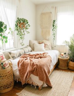 a bed with blankets and pillows on top of it in a room filled with potted plants