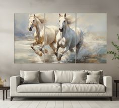 two white horses running through the water on a canvas in a living room with wood flooring