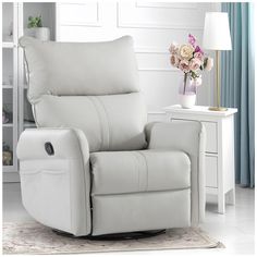 a white leather recliner chair sitting on top of a rug next to a table