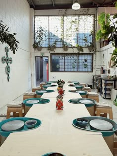 a long table with plates on it in a room filled with plants and potted plants