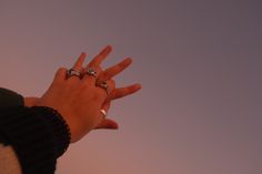 a woman's hand reaching up into the sky with two rings on her fingers