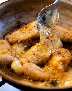 a spoon is being used to stir food in a skillet with chicken and potatoes