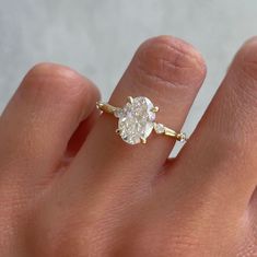 a woman's hand with a diamond ring on top of her finger, showing the center stone