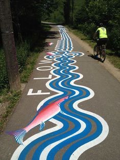 a man riding a bike down a street next to a painted road