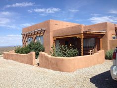 a car is parked in front of a adobe - style house with an attached porch