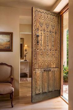 an ornate wooden door is open to the living room and dining area, with a chair next to it