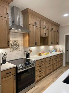 a kitchen with wooden cabinets and white counter tops, stainless steel range hood over the stove