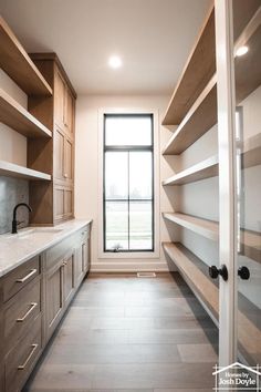 an empty walk in closet next to a window with lots of shelves on the wall