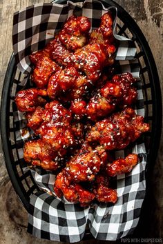 chicken wings with sesame seeds and teriyaki sauce in a basket on a wooden table