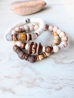 Soft, serene, cozy, and beachy. Beautiful beige, white, caramel, brown, and ecru in these mixed medium stack bracelets. Several creamy Fossilized Coral, and Picture Jasper gemstone beads in different sizes and colors. Large ethical bone beads, matte sea shells dyed in a soft white, natural coconut disk beads, rustic antique beads, and African recycled glass. Mix in with an array of mixed metals, and cluster accents of mixed gemstone beads including pearls. Unique and stunning. The item/s picture Brown Natural Stone Beaded Bracelets For Beach, Brown Beaded Bracelets With Natural Stones For Beach, Brown Natural Stones Beaded Bracelets For Beach, Earthy Brown Beaded Bracelets For Beach, White Bohemian Stackable Bracelets, Bohemian White Stackable Bracelets, Earthy Brown Bracelet For Beach, Earthy Brown Bracelets For Beach, Earthy Brown Bracelets For The Beach