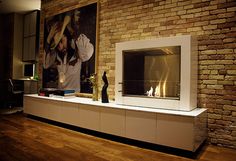 a living room with a fire place in the center and a brick wall behind it