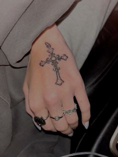 a woman's hand with a cross tattoo on it