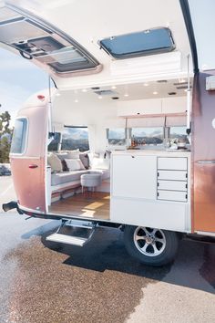 the interior of a camper trailer with its door open and furniture in it's back