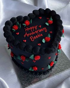 a black cake with red roses on it and the words happy anniversary bosia written on top