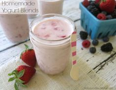 some strawberries and yogurt are sitting on a table next to milkshakes