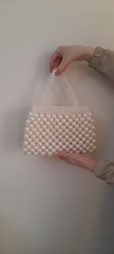 Step into the realm of opulence with this exquisite pearl beaded purse! 🌟 Every bead on this handbag has been meticulously placed, reflecting the craftsmanship and passion behind its creation. The gleaming pearls come together in a luxurious pattern, radiating an ethereal charm that's hard to resist. Perfectly suited for elegant soirées, weddings, or any event where you aim to make a statement. But this handbag isn't just about its striking appearance. Its spacious interior ensures that you can Pearl Purse Making, Pearl Beaded Evening Bag For Formal Occasions, Formal Beaded Pearl Evening Bag, Beaded Pearl Bags For Parties, Rectangular Pearl Evening Bag With Pearl Embroidery, Handmade Pearl Evening Bag In Cream, Handmade Cream Pearl Evening Bag, White Pearl-embellished Bags, Pearl White Rectangular Pearl Evening Bag