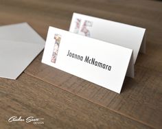 two folded business cards sitting next to each other on a wooden table with a white envelope