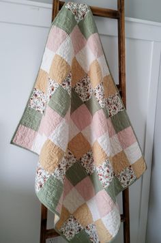 a quilt hanging on a ladder in a room