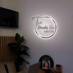 the beauty bar and boutique logo is lit up above a desk with a laptop on it