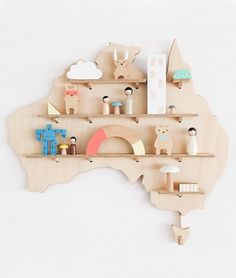 a wooden australia map with animals and toys on the shelves in front of white wall