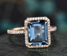 a blue and white diamond ring sitting on top of a black stone surface with diamonds around it