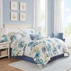 a bedroom with blue walls and white bedding in front of a window that has pictures on the wall