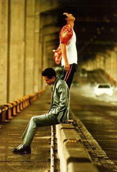 a man and woman standing on the side of a bridge