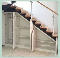 an empty room with some shelves under the stairs and a closet underneath the stair case