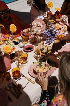 a group of people sitting around a table with plates and bowls of food on it