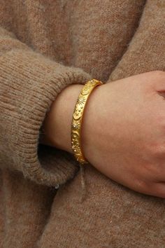 A woman wearing a gold bangle. Celestial Bangle Bracelets For Gift, Adjustable Celestial Bracelets With Sun And Moon Design, Adjustable Celestial Sun And Moon Bracelets, Adjustable Sun And Moon Celestial Bracelets, Spiritual Gold Bracelets With Moon Phase Detail, Spiritual Gold Bracelets With Moon Phase, Celestial Moon Phase Bracelets, Celestial Jewelry, Star Studs