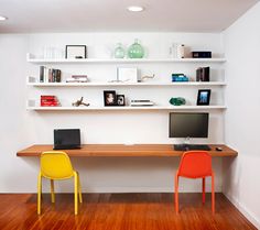 two chairs and a desk in front of a wall with shelves on the opposite side