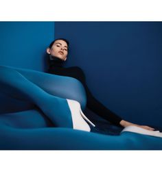 a woman laying on top of a blue couch