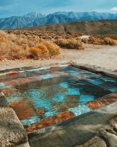 a pool in the middle of nowhere with mountains in the background