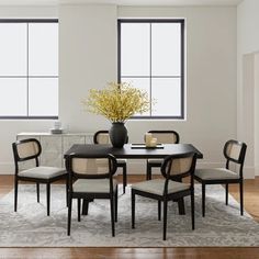 a dining room table with chairs and a vase filled with flowers on top of it