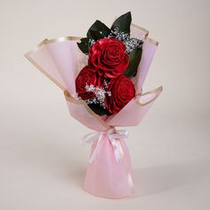 a bouquet of red roses wrapped in pink paper