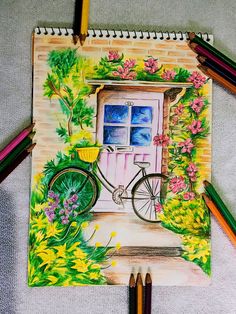 a drawing of a house with a bicycle and flowers on the front door, surrounded by colored pencils